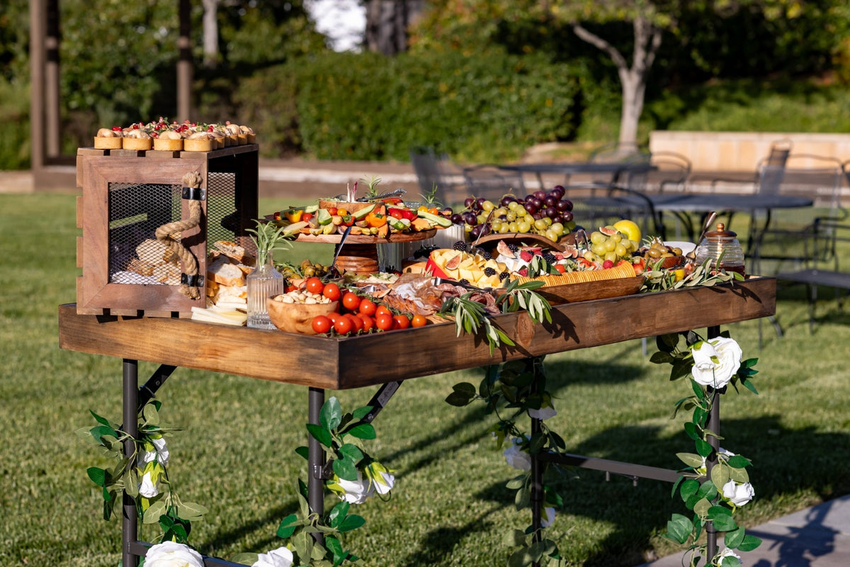 Wooden charcuterie serving board topper outdoors with vegetable and fruit spread