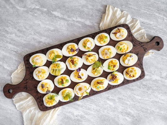 Dark walnut deviled egg serving tray with round wells and side handles, filled